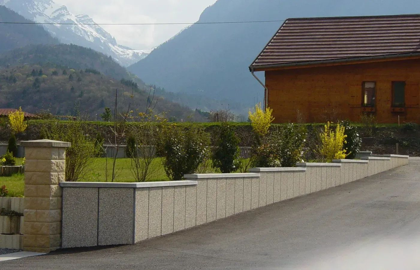 Muret décoratif Prémurette® à parement pierre, devant une maison en montagne